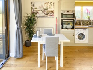 A modern kitchen with a dining table, chairs, a potted plant, and a painting on the wall. - Woodside Retreat, Number 37 (Newbold Coleorton)