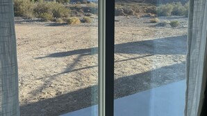 A view through a window with a clear sky, a desert landscape, and distant mountains.