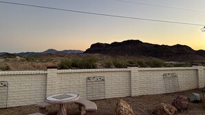 A desert landscape with a brick wall, a small table, and a rock garden.