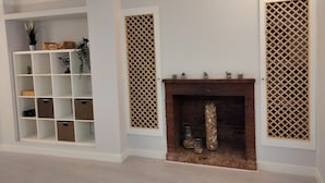 A room with a white fireplace, a white shelving unit with various items, and a lattice screen on the wall. - Double room in the heart of the old town of La Nucía (La Nucía)