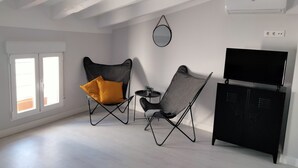 A modern living room with two black armchairs, a black TV stand, and a white air conditioning unit. - Double room in the heart of the old town of La Nucía (La Nucía)