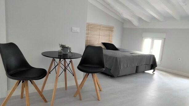 A modern bedroom with a bed, two black chairs, a small round table, and a potted plant. - Double room in the heart of the old town of La Nucía (La Nucía)