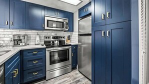Uma cozinha moderna com armários azuis, eletrodomésticos de aço inoxidável e painel de azulejos.