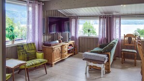 Un salon chaleureux avec un plancher en bois, un canapé vert, un meuble en bois et un téléviseur.