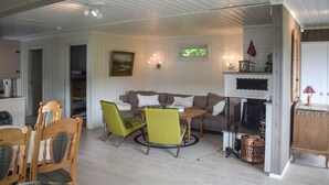 Un salon chaleureux avec un canapé, deux fauteuils, une petite table et une cheminée.