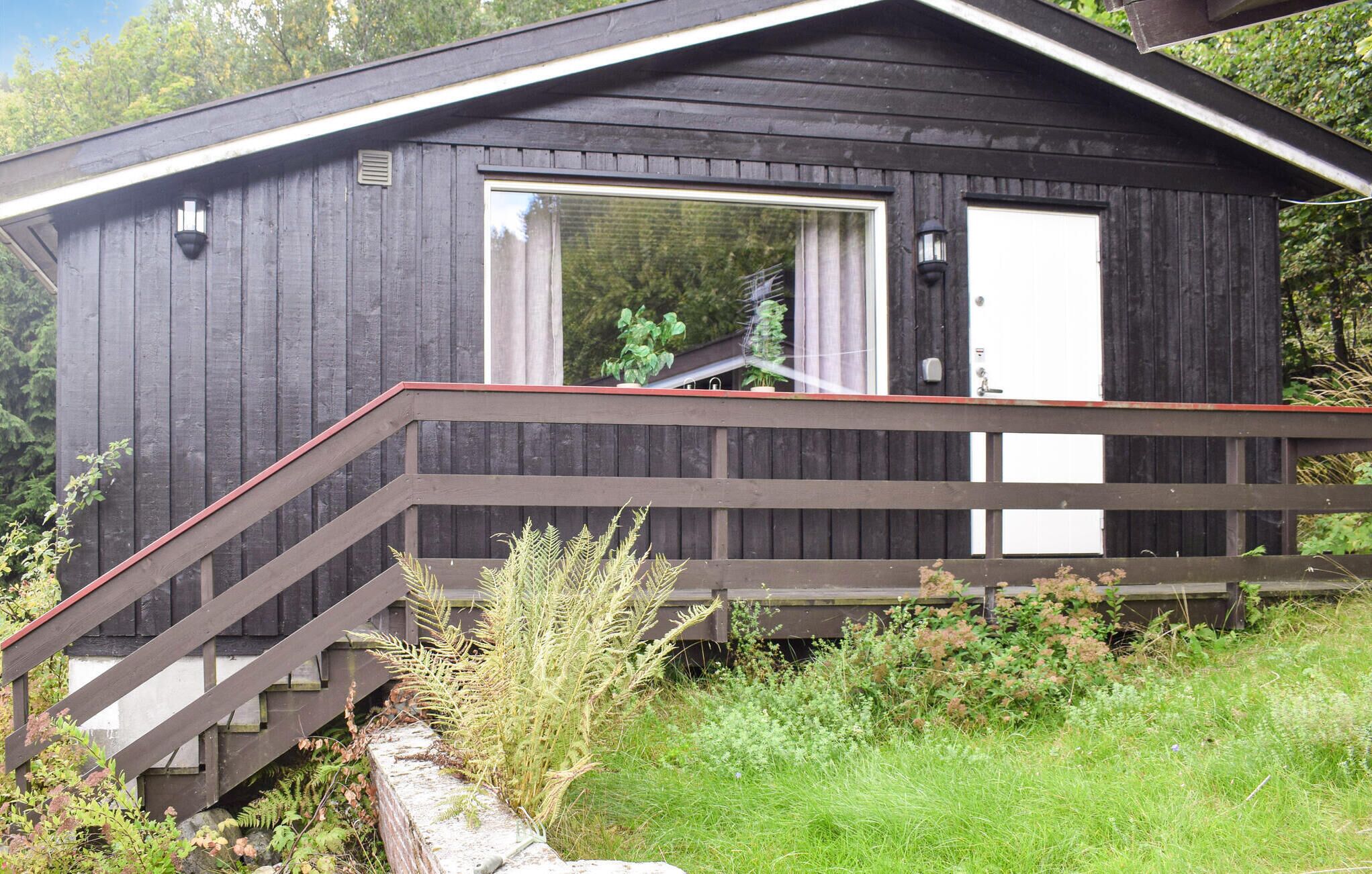 Une petite cabane avec une façade en bois, une porte d’entrée et un escalier menant à une véranda.