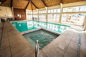 Una piscina interior con suelo de baldosas y techo de madera.