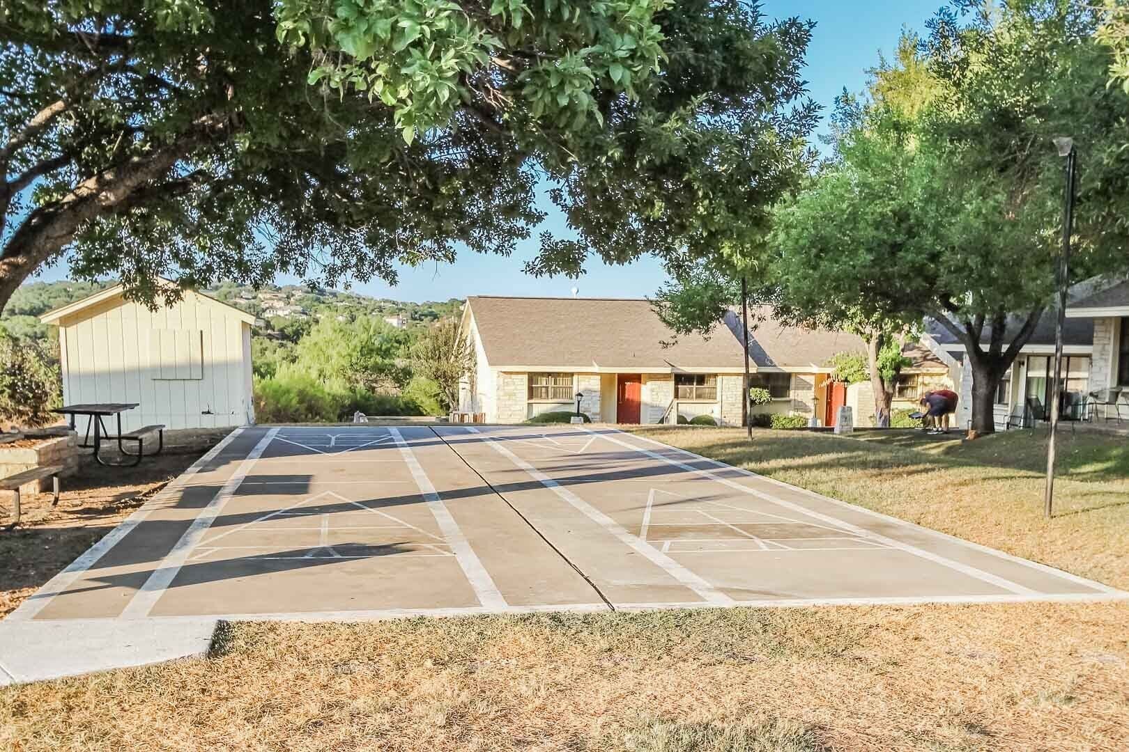 A residential area with a paved driveway leading to a house with a stone facade and a red door.