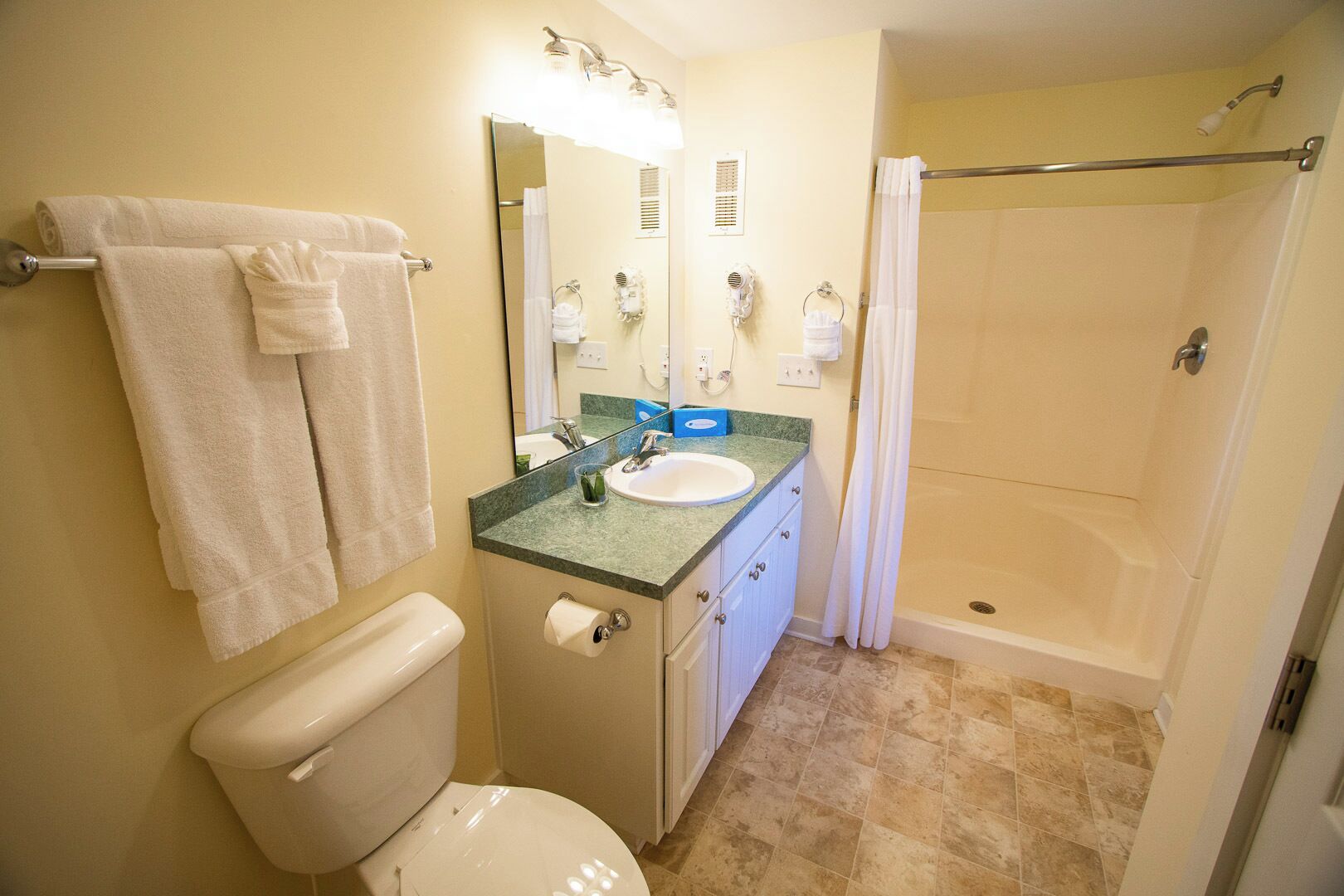 Ein Badezimmer mit Toilette, Waschbecken, Spiegel, Dusche und Handtuchhalter.