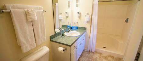 A bathroom with a toilet, sink, mirror, shower, and towel rack.