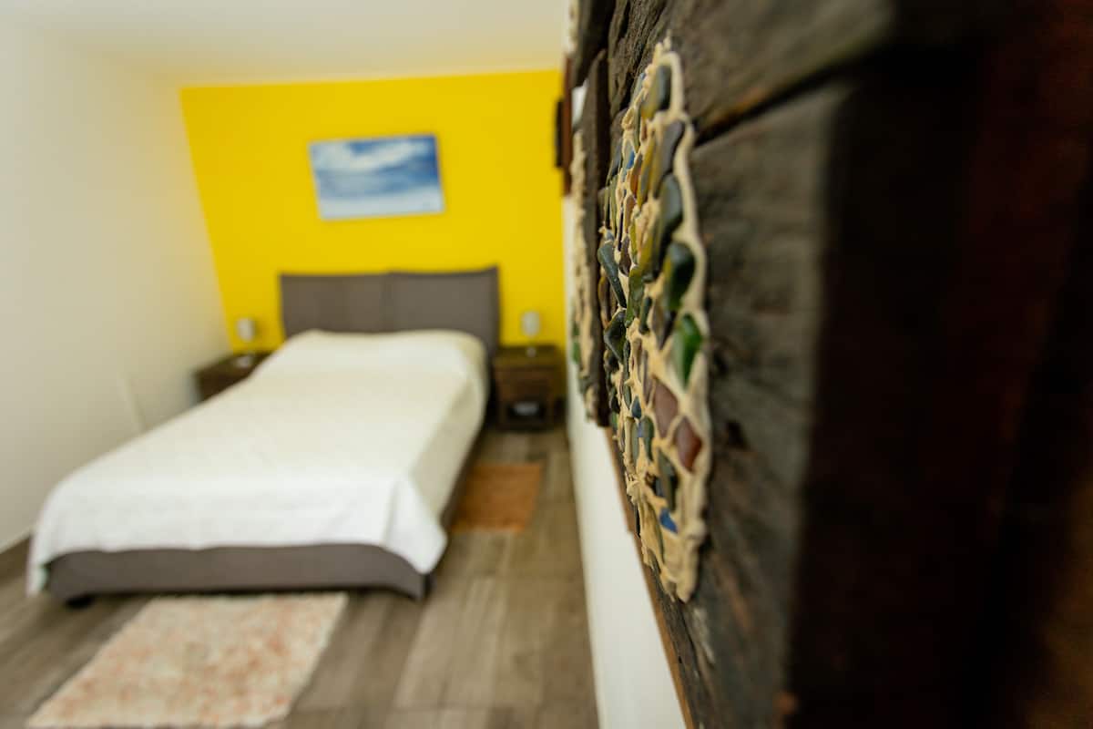 A bedroom with a bed, a nightstand, and a wall with a mosaic.