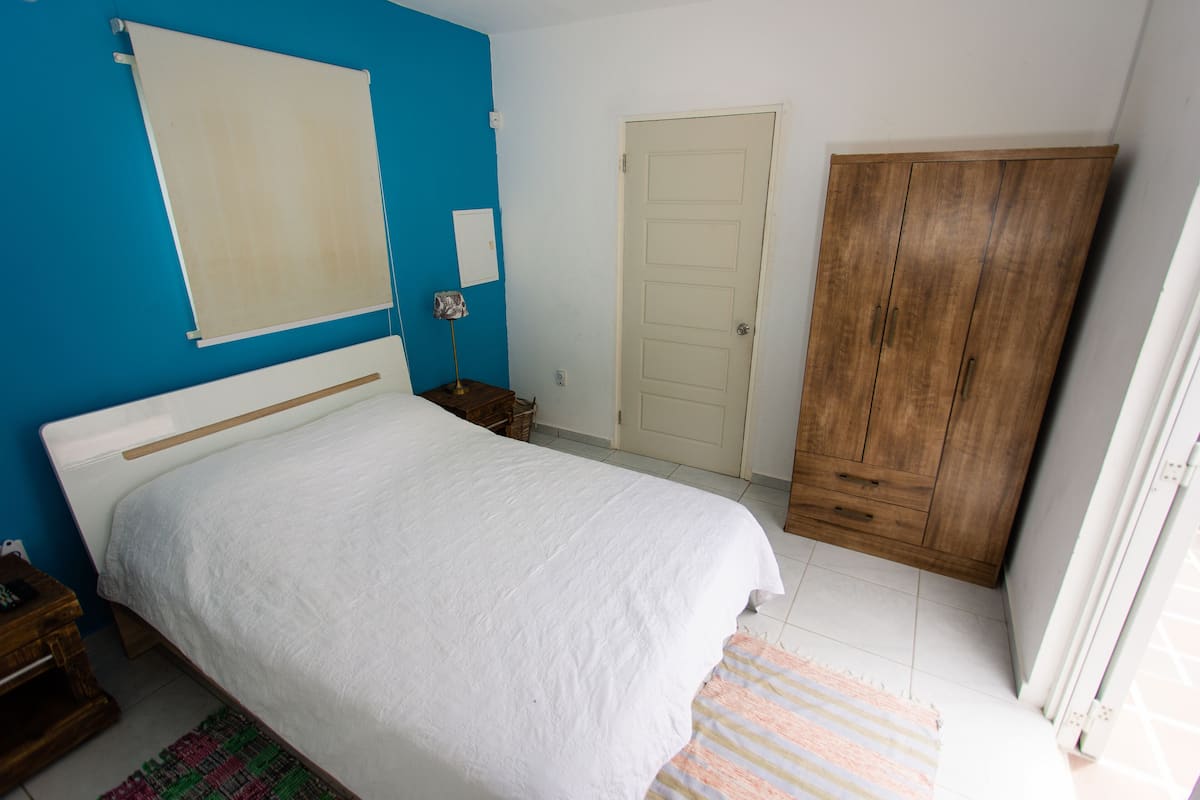 A bedroom with a bed, a wardrobe, a door, and a nightstand.