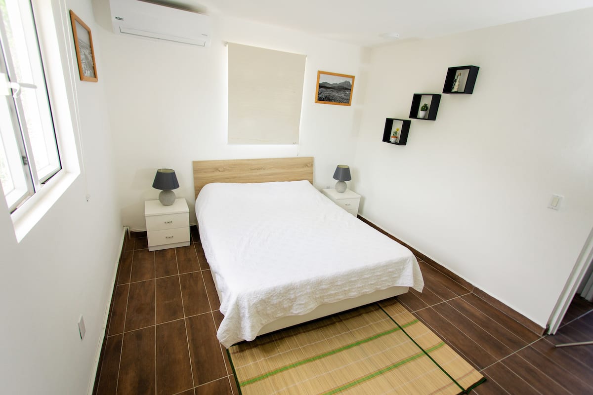A bedroom with a bed, bedside tables, a window, and wall-mounted pictures.
