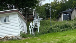 Een wit huis met een stenen muur en een houten trap naar een terras.