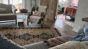 Een gezellige woonkamer met een bank, fauteuil en een kleurrijk vloerkleed.
