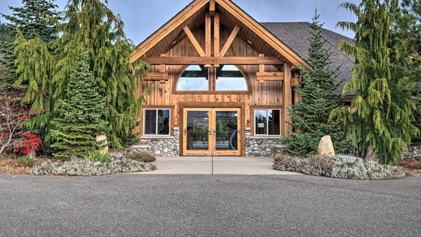 Un chalet en bois à la façade symétrique, doté de grandes portes vitrées et d’une fondation en pierre.