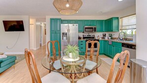 Una cocina moderna con armarios verde azulado, un refrigerador de acero inoxidable y un microondas.