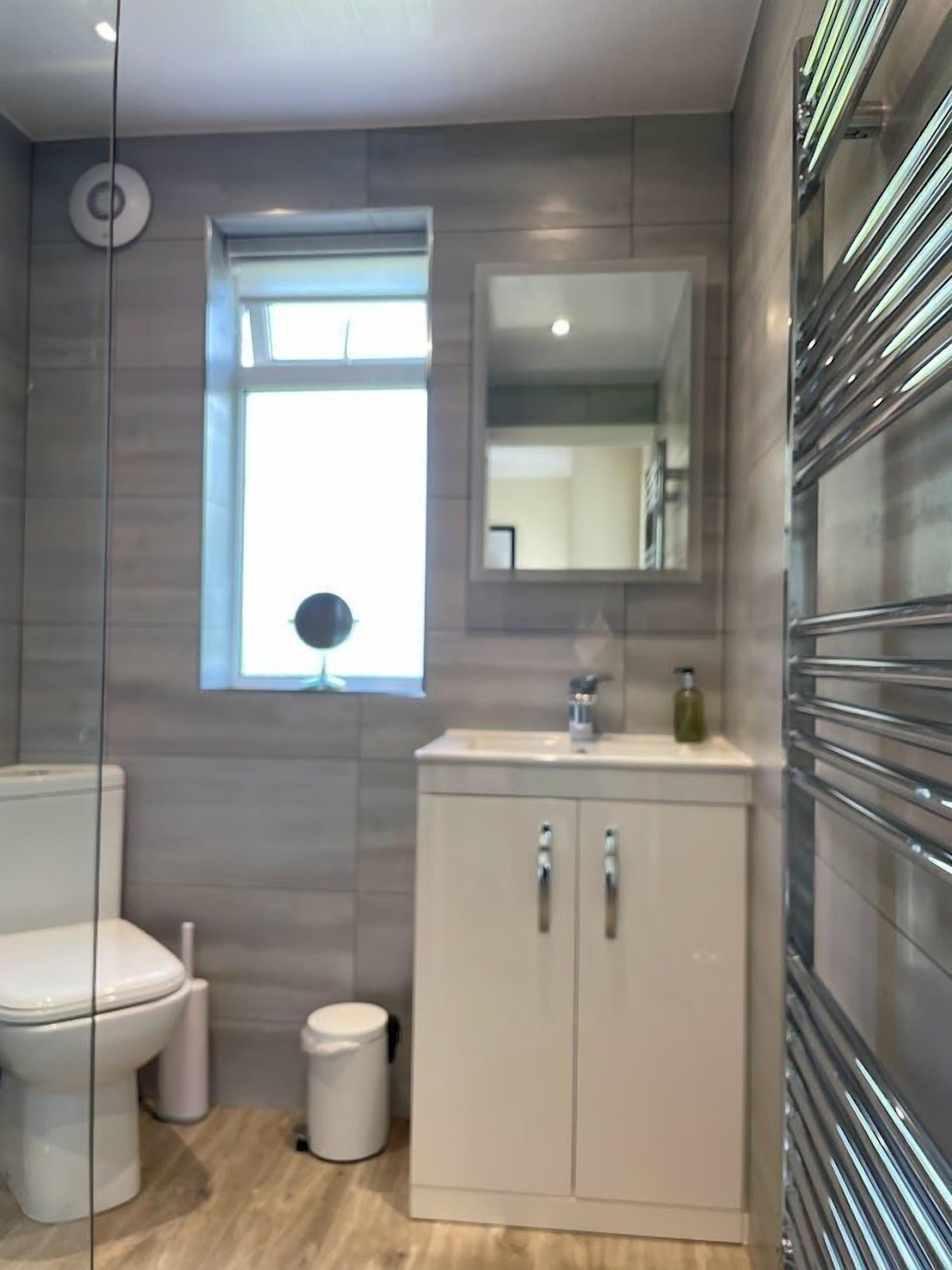Ein modernes Badezimmer mit Toilette, Waschbecken und Schrank, mit einem Fenster und einem Spiegel.