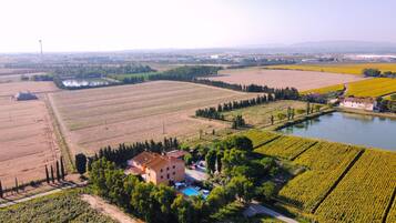 A rural landscape with fields, a pond, and a building with a swimming pool.