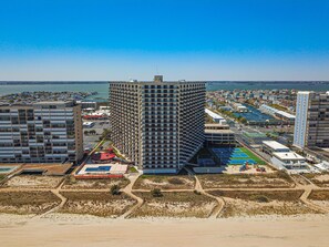 A high-rise hotel with a unique angular design, located near a beach with a view of the sea. - OCEAN FRONT Gem w/Pools, Movie Theater, Game Room, SunsetCove at SeaWatch (Ocean City)