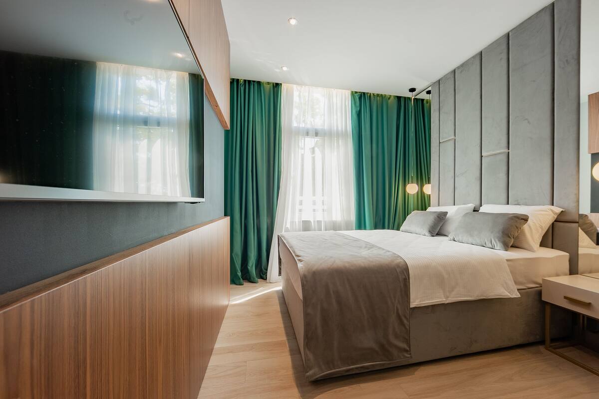 Un dormitorio moderno con cama, mesita de noche y televisor montado en la pared.