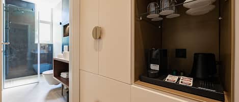 A modern bathroom with a shower, toilet, and a coffee machine on a shelf.