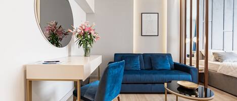 A modern living room with a sofa, a desk, a chair, a coffee table, and a mirror.