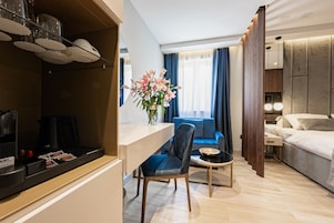 Una habitación de hotel moderna con comedor, sofá, cama y un jarrón de flores.