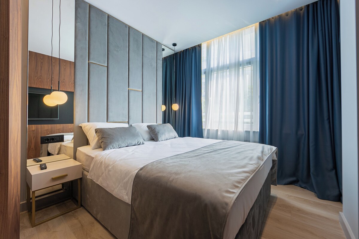 A modern bedroom with a large bed, bedside tables, and a wardrobe.