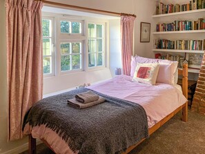 Quarto com cama, janela, estante e cortina.