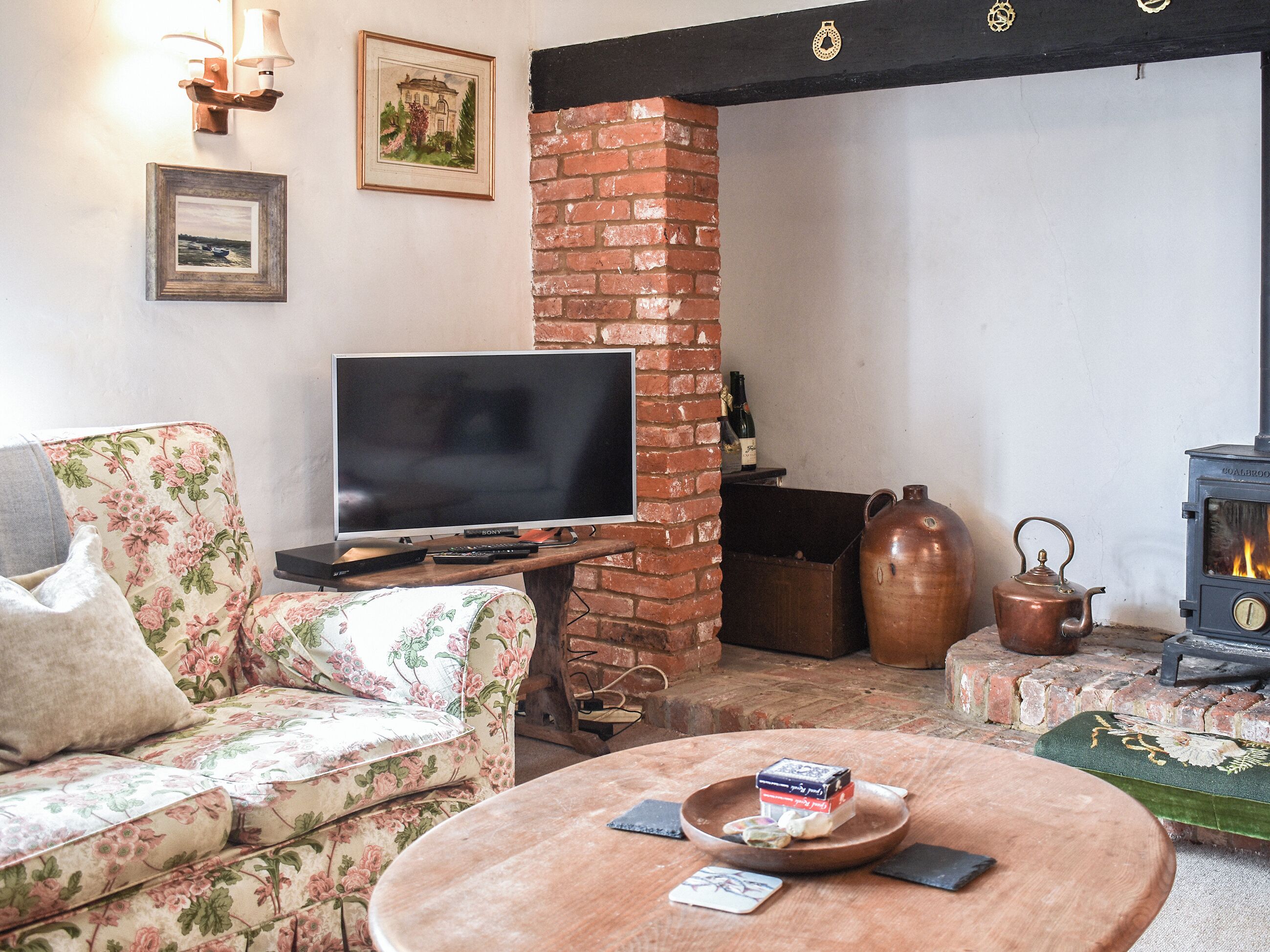 Een woonkamer met een televisie, een open haard, een bank en een salontafel.
