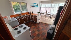 A kitchen with a stove, sink, and dining area with chairs and a table.