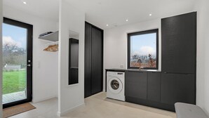 Eine moderne Küche mit eingebauter Waschmaschine, einem großen Fenster und Blick ins Freie.