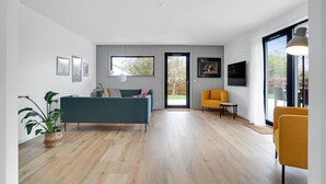 Ein modernes Wohnzimmer mit einer Couch, Sesseln und einem Fernseher.