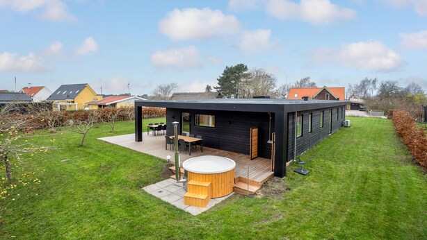Ein modernes Haus mit Terrasse, Whirlpool und einer Holzdeck.