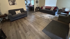 A spacious living room with two sofas, a dining area, and a kitchen in the background. - Downtown Taber Street Railroad 🚂 House - Great Location!! (Williams)