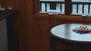 Een kamer met houten lambrisering en een raam met uitzicht op een terras. Een tafel met een bord eten is zichtbaar.