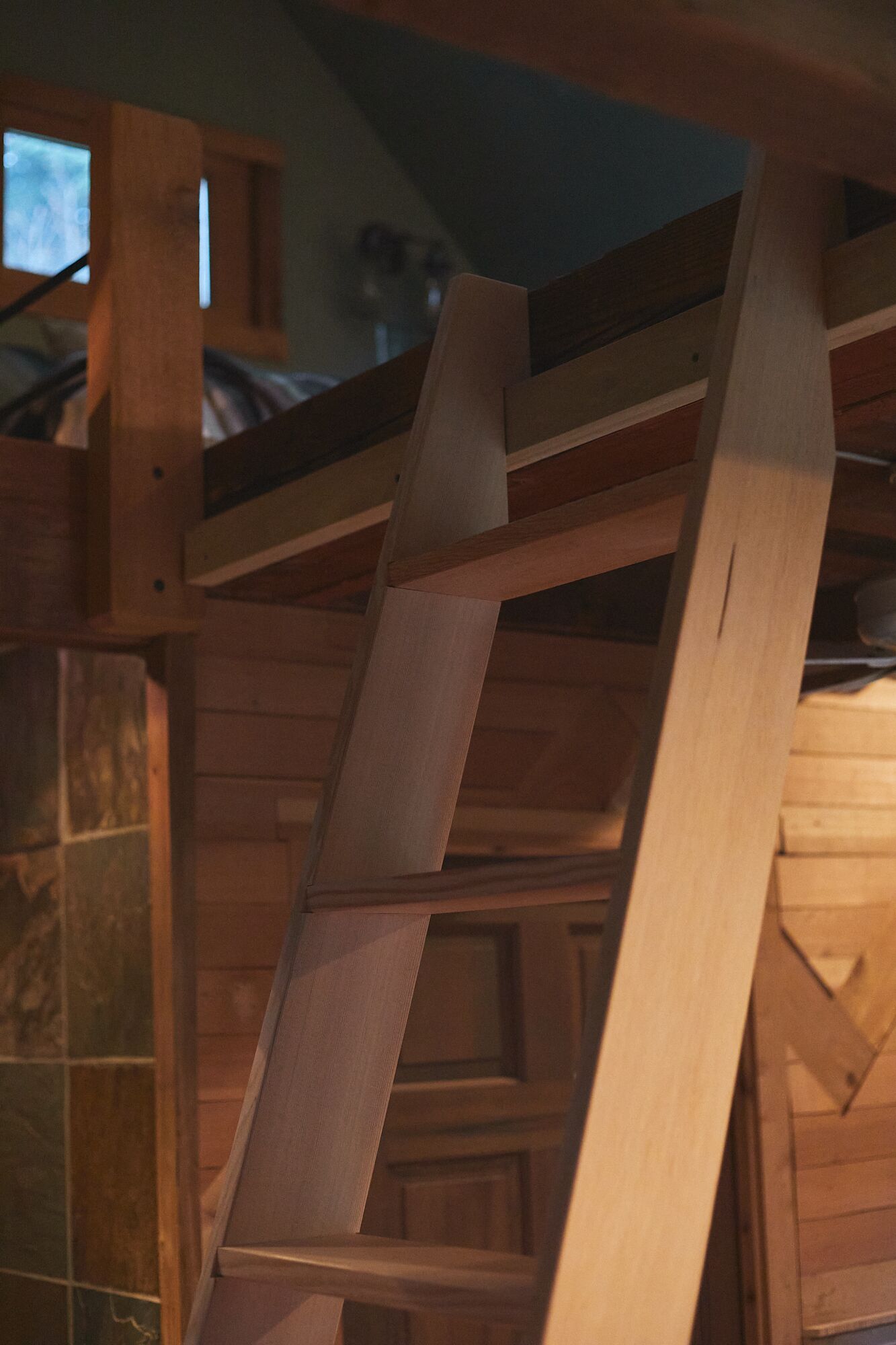 Une structure d’escalier en bois, avec un mur recouvert de carreaux et une fenêtre.