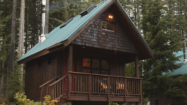 Een chalet met een houten gevel, een balkon en een schoorsteen.