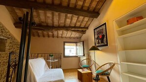 A cozy room with a bed, a chair, a small table, and a shelf. - Laura's House (Castelcucco)