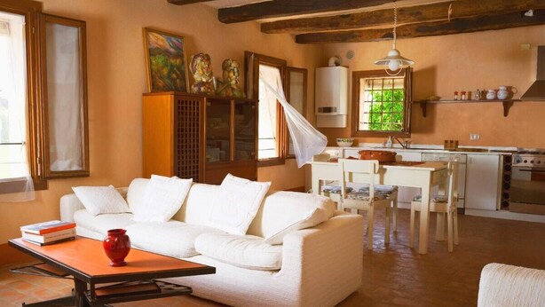 A cozy living room with a white sofa, a coffee table, and a dining area with a table and chairs. - Laura's House (Castelcucco)