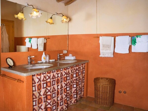 A bathroom with a patterned shower curtain, a sink with a mirror, and a hanging towel rack.
