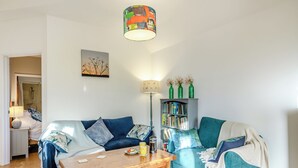 A living room with a sofa, a coffee table, a bookshelf, and a painting on the wall. - 1 bedroom accommodation in Diss (Diss)