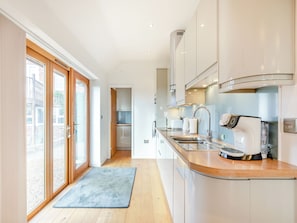 A modern kitchen with a large window, a built-in oven, and a coffee machine. - 1 bedroom accommodation in Diss (Diss)