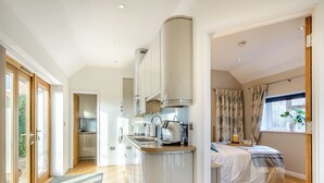 Eine moderne Küche mit Kochinsel, ein Essbereich mit Tisch und Stühlen sowie ein Schlafzimmer mit Bett und Fenster.