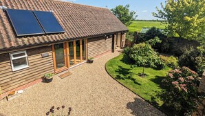 A wooden house with solar panels, a gravel driveway, and a garden. - 1 bedroom accommodation in Diss (Diss)