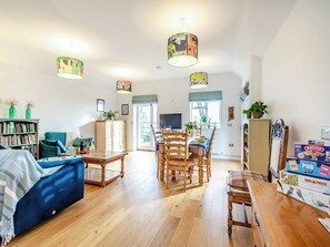 A spacious living room with a dining area, wooden furniture, and a bookshelf. - 1 bedroom accommodation in Diss (Diss)