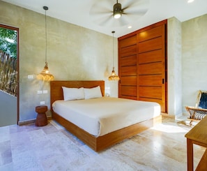 A bedroom with a large bed, wooden headboard, two pendant lights, a ceiling fan, and a wooden wardrobe.