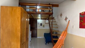 A room with a hammock, a wooden cabinet, a staircase, and a blue couch. - Casas Vasconcelos (Itacaré)