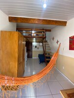 Um quarto com rede, um armário de madeira, uma escada e um sofá azul.